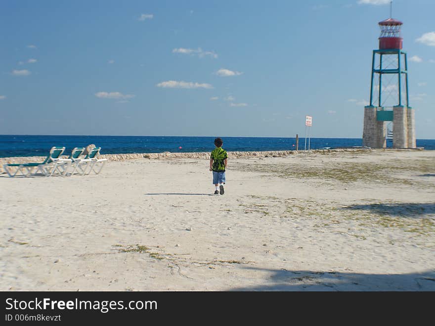 Boy walking on private beach with watch tower and empty beach chairs. Boy walking on private beach with watch tower and empty beach chairs