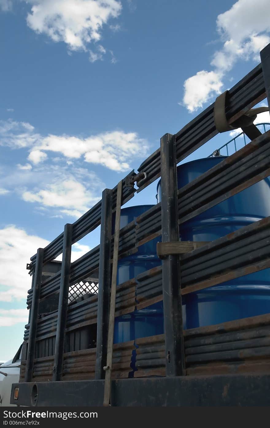 A work truck with cans of oil in the back and clouds