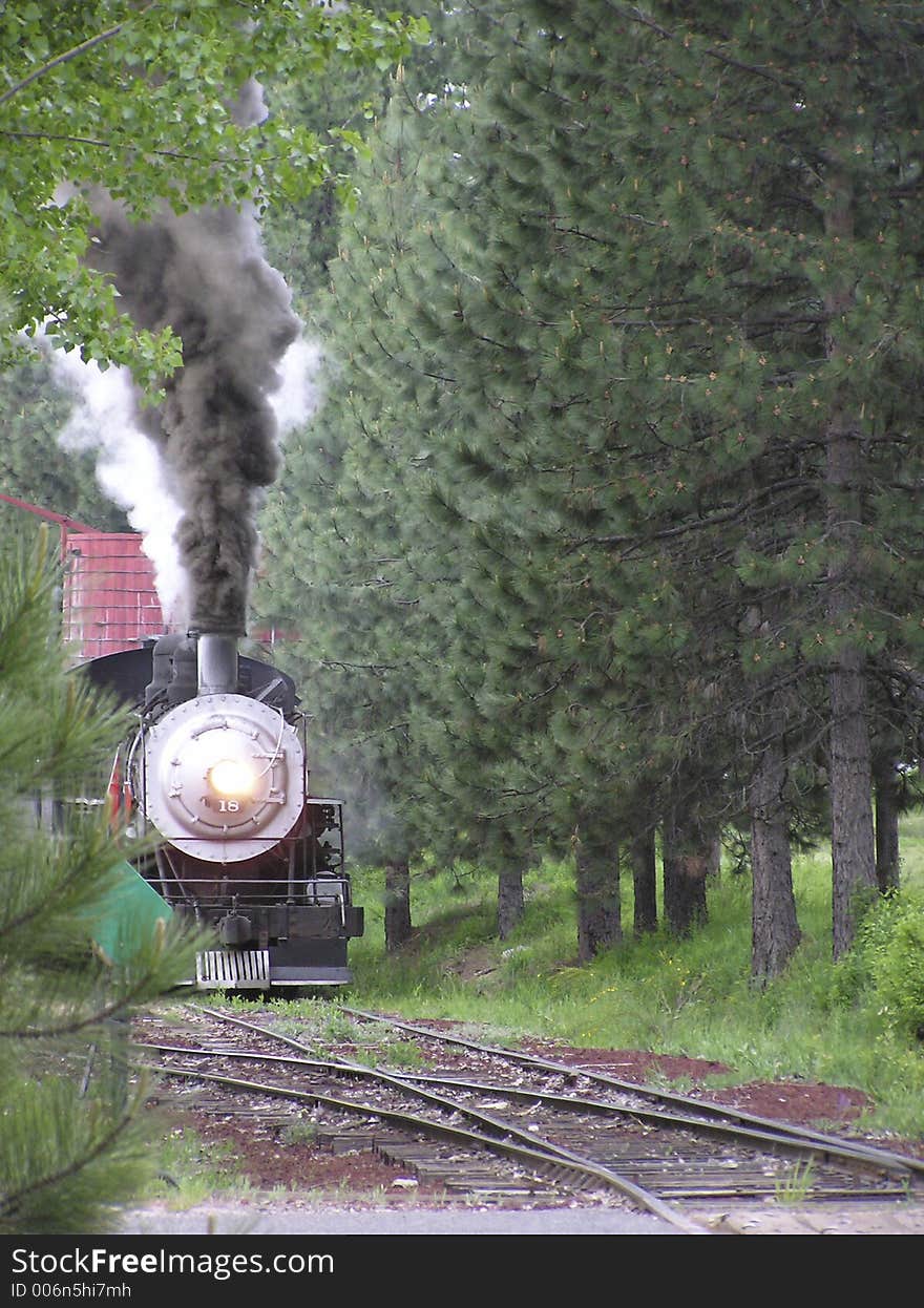 An old Steam locomotive puffs hard leaving the station. An old Steam locomotive puffs hard leaving the station