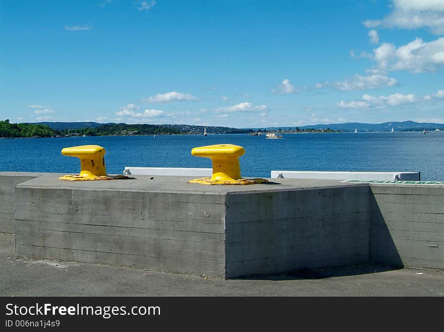 Two yellow cleats at the harbour of Oslo with view to the Oslofjord. Two yellow cleats at the harbour of Oslo with view to the Oslofjord.