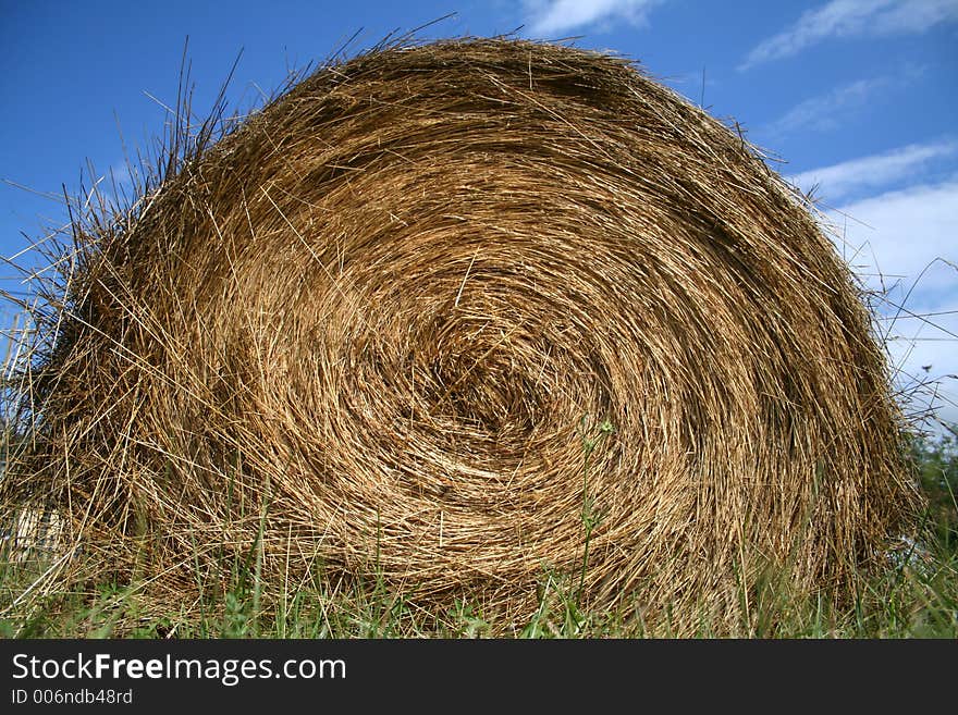 Hay ball in the grass, on a blue sky day