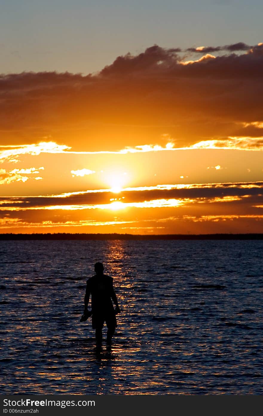 A young man wades into the lake at susnet. A young man wades into the lake at susnet.