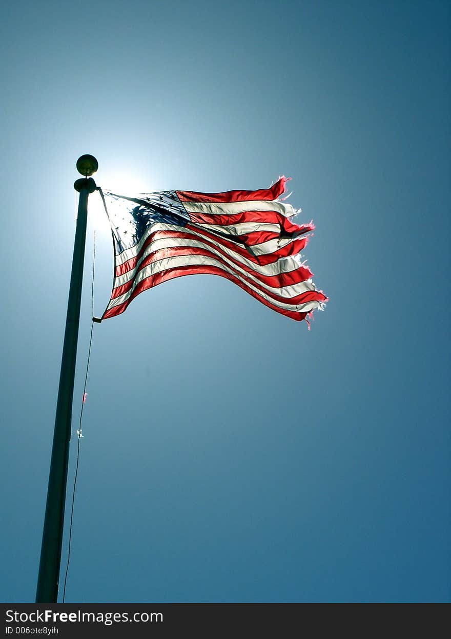 A flag waving in the breeze with the sun illuminating it from behind. A flag waving in the breeze with the sun illuminating it from behind