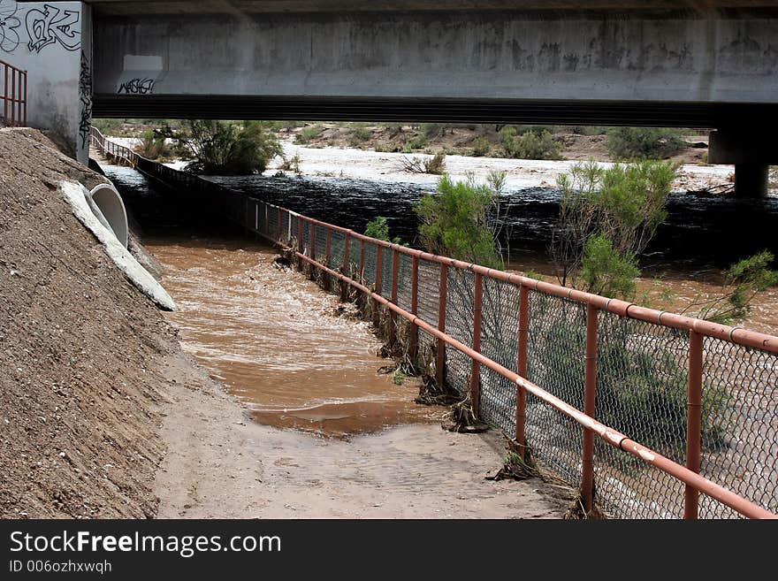 Flood waters flowing down a desert wash under the highway. Flood waters flowing down a desert wash under the highway.