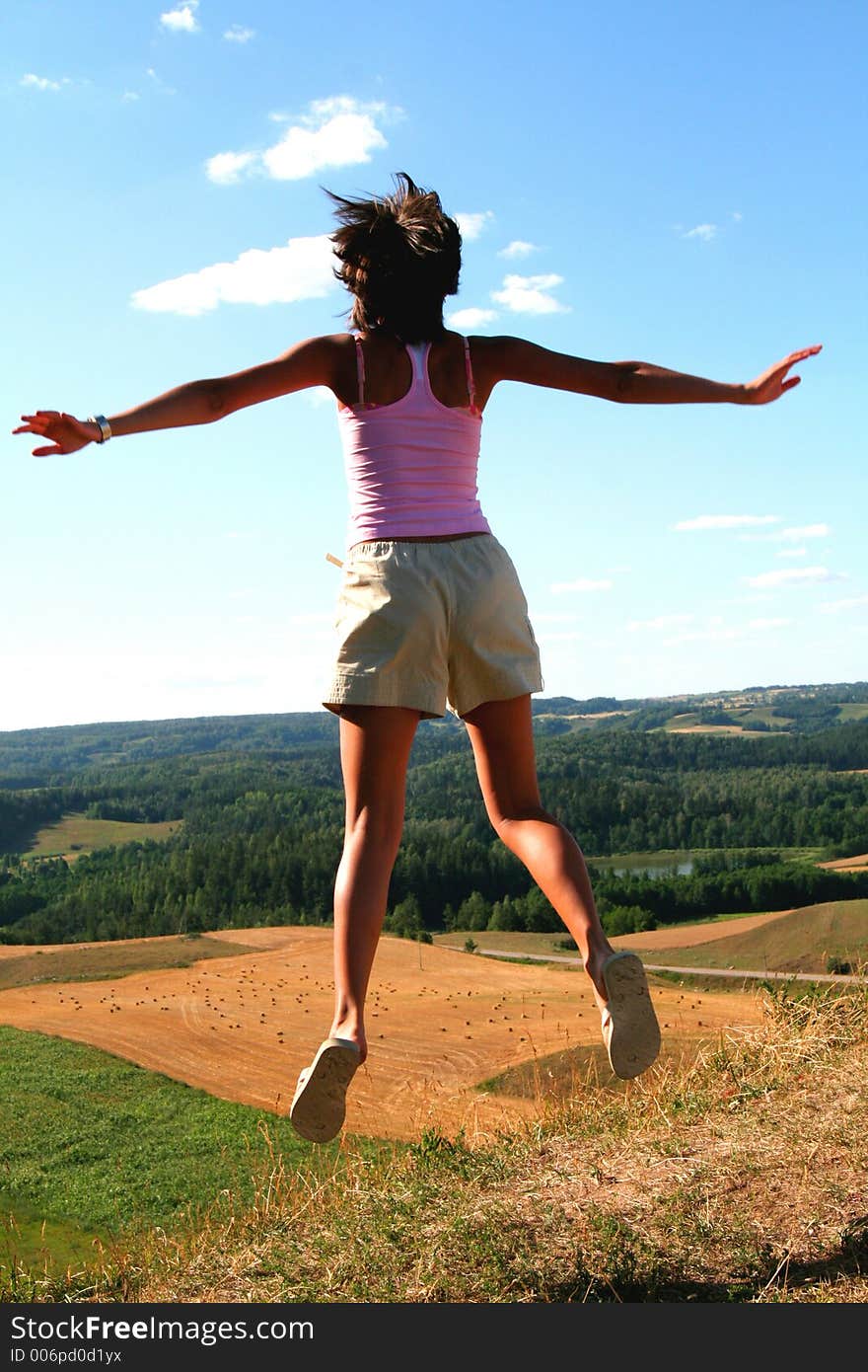 A young girl jumping up, beautiful country view in background. A young girl jumping up, beautiful country view in background