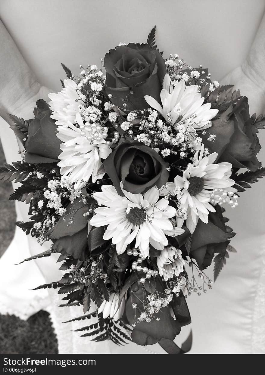 Bride holding her wedding bouquet against her dress in black and white