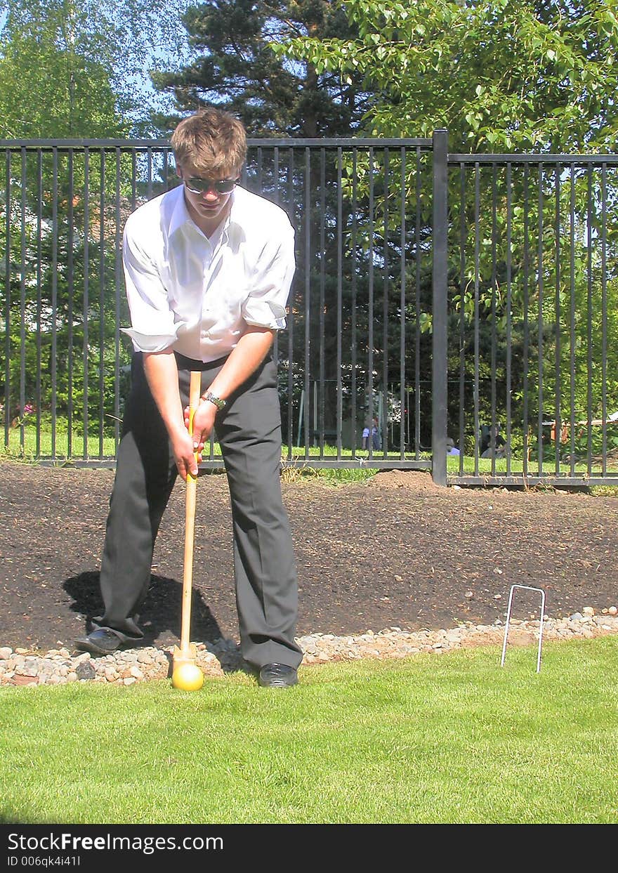 A picture of jonny lining up for the shot in a casual game of back yard croquet. A picture of jonny lining up for the shot in a casual game of back yard croquet