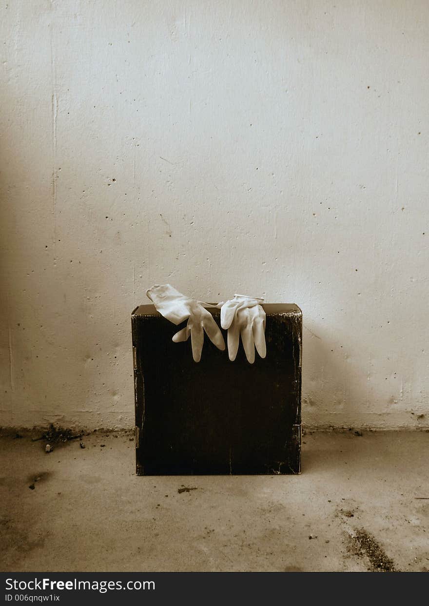 A photo of a pair of latex gloves on a black paper box slightly enhanced to look eerie. A photo of a pair of latex gloves on a black paper box slightly enhanced to look eerie