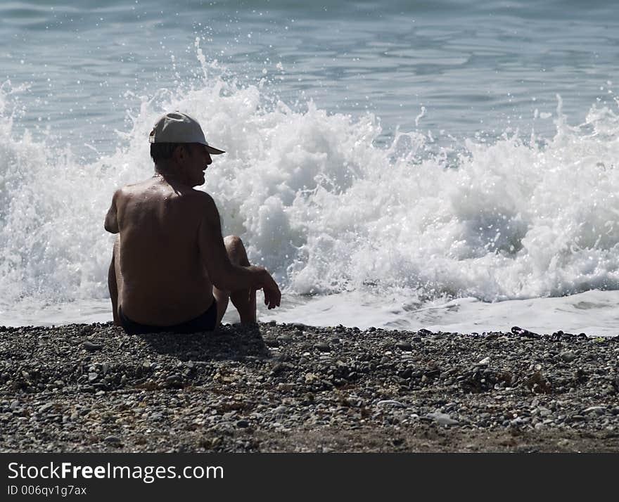 Waves breaking in front of man on beach.