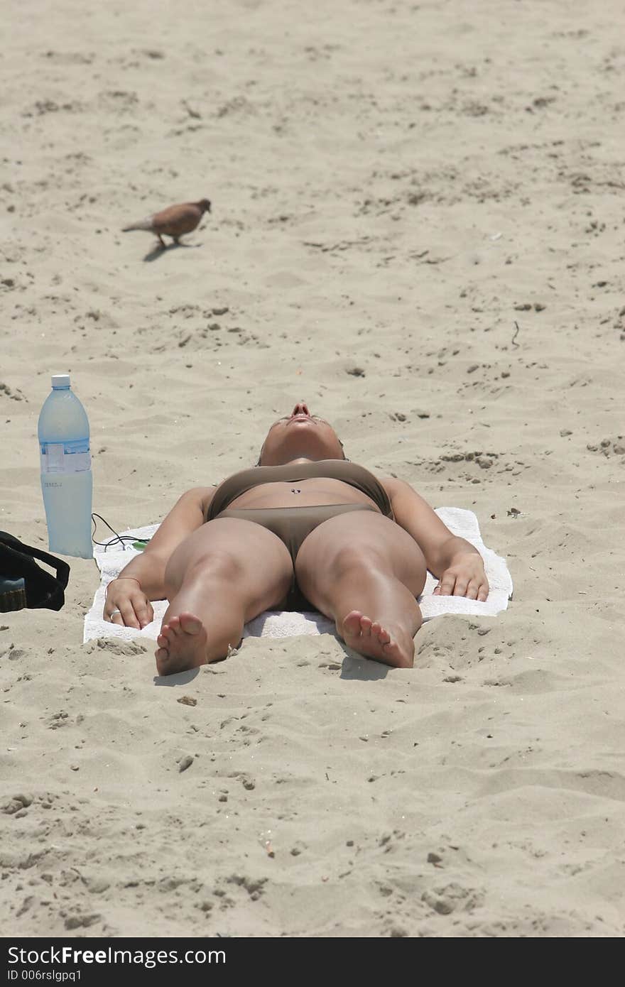 Woman sunbathing, with a cool bottle of water by her side