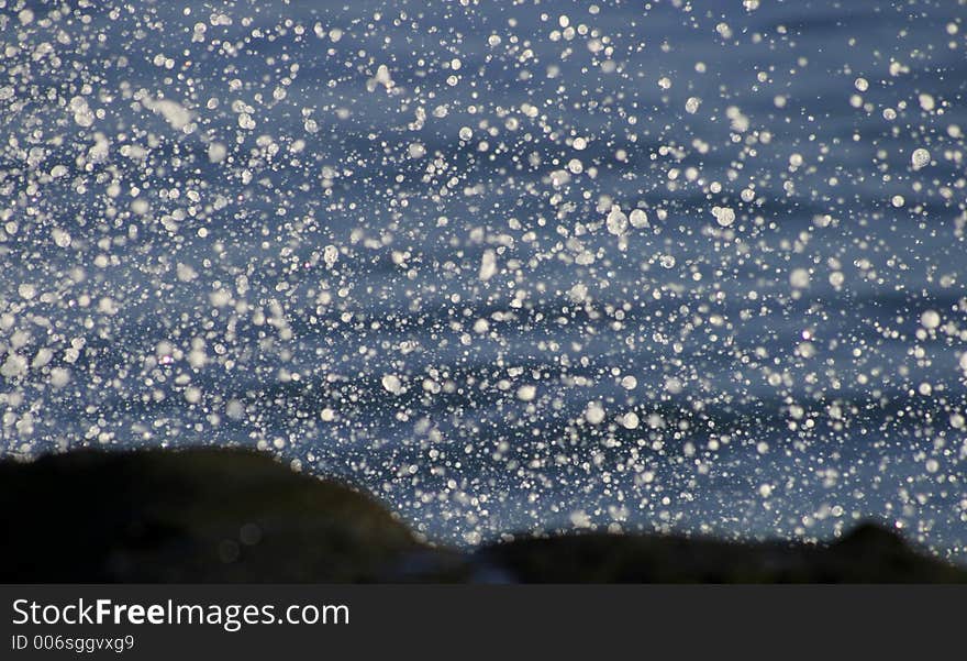 Close-up of sea spray over shoreline lava rocks