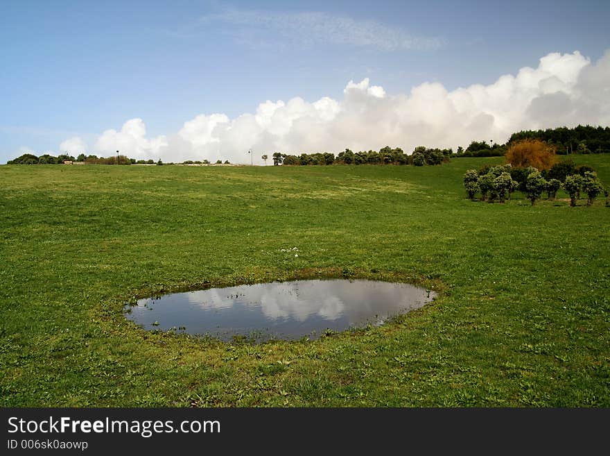 Green field - Landscape green grass, blue sky, white clouds and a lake