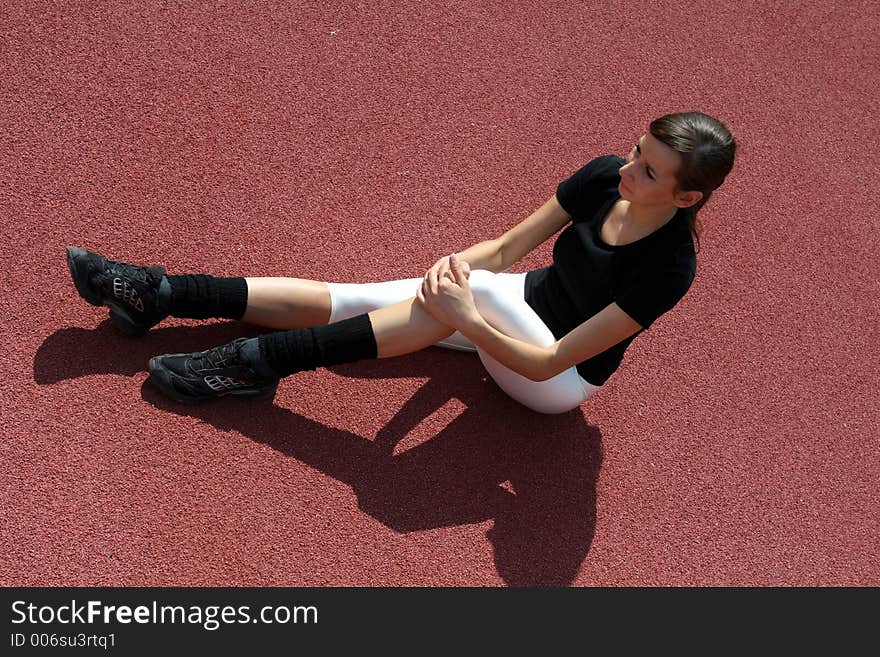 A young girl stretching on the track. A young girl stretching on the track