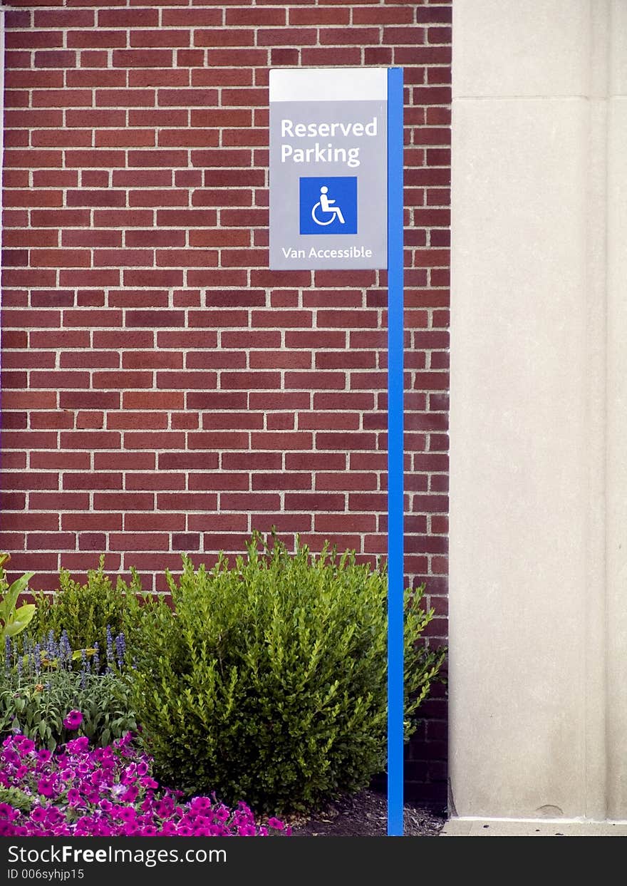 Handicaped parking sign outside of a brick building.