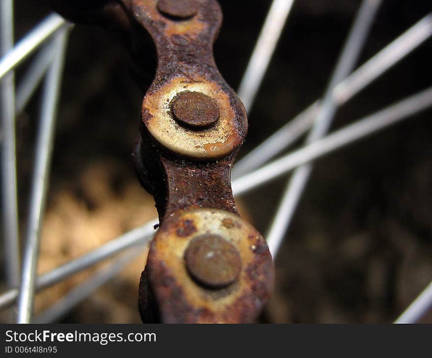 Up close of a rusted bike chain with the spokes in the background