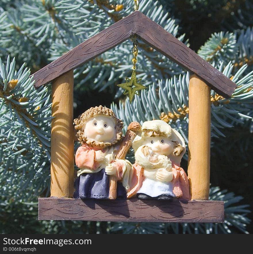 Jesus, Mary and Joseph sit inside the frame of a building, with a Gold star over their heads. This special ornament is hanging on a fir tree. Jesus, Mary and Joseph sit inside the frame of a building, with a Gold star over their heads. This special ornament is hanging on a fir tree.