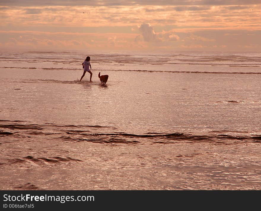 Girl playing in ocean waves with her dog. Girl playing in ocean waves with her dog