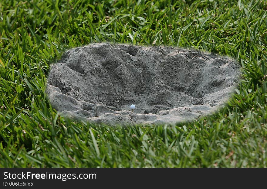 Golf ball in a hole of sand