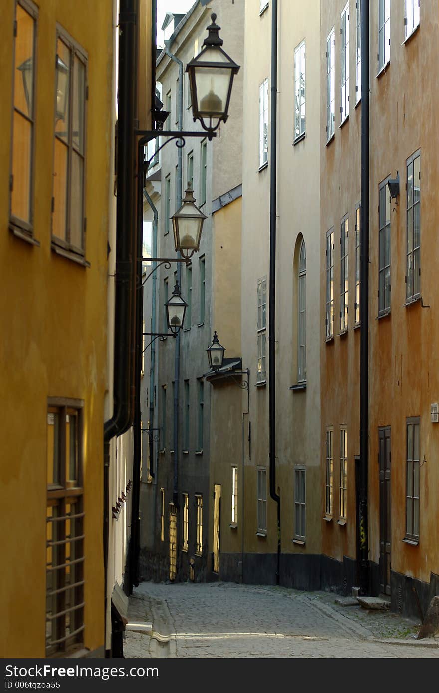 Narrow street with an array of streetlights hanging from buildings in Stockholm, Sweden