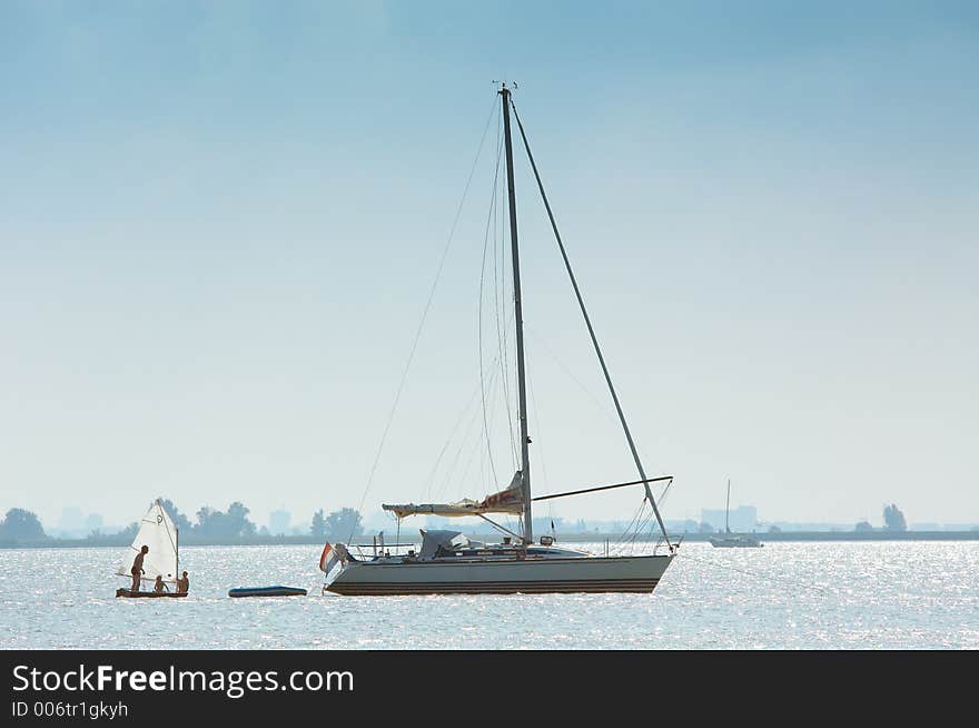 A very small and a big sailboat. A very small and a big sailboat