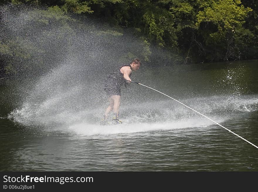 Wakeboarder throwing up water beside boat