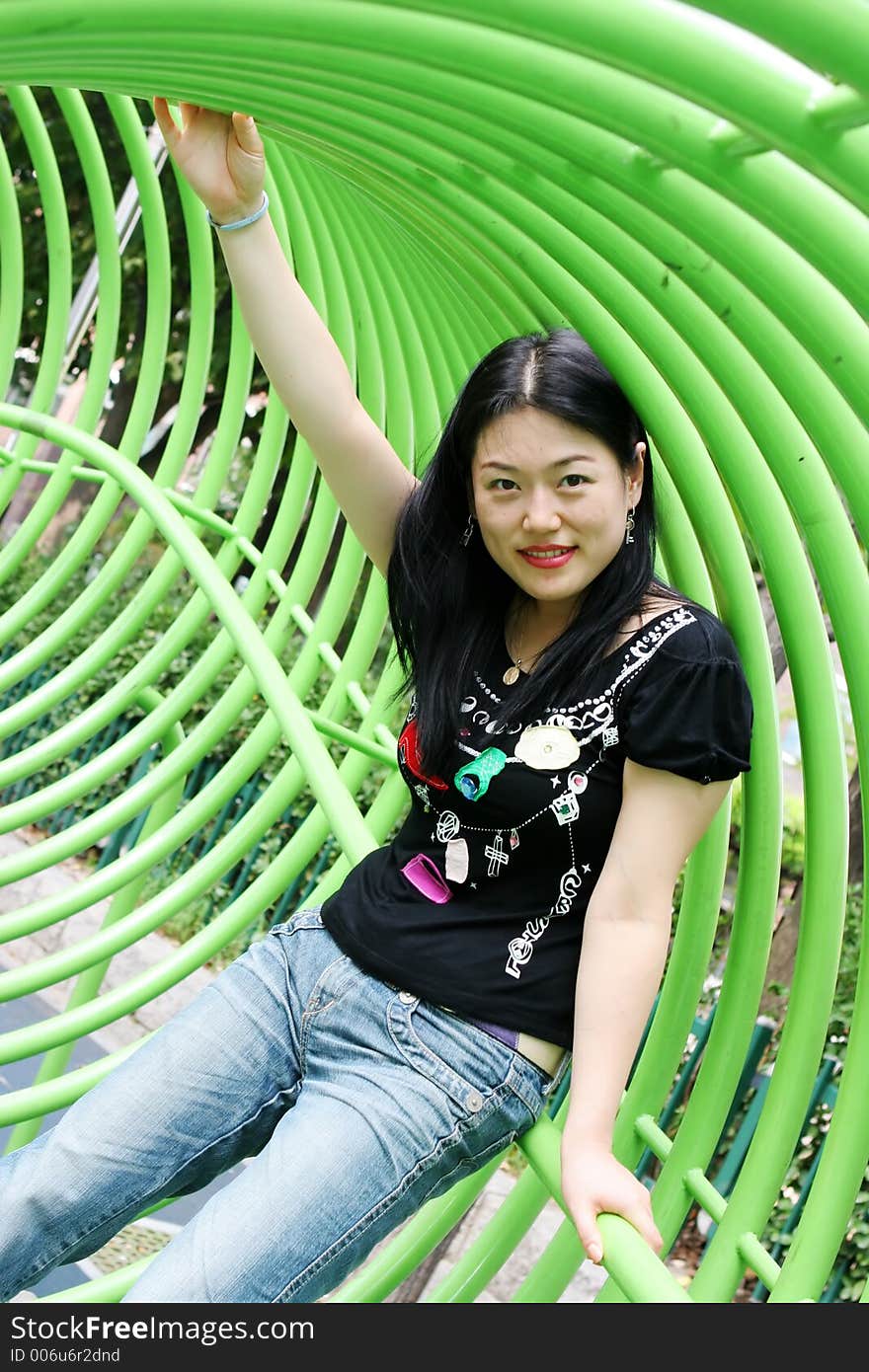 Asian woman playing in a green tunnel at the park. Asian woman playing in a green tunnel at the park