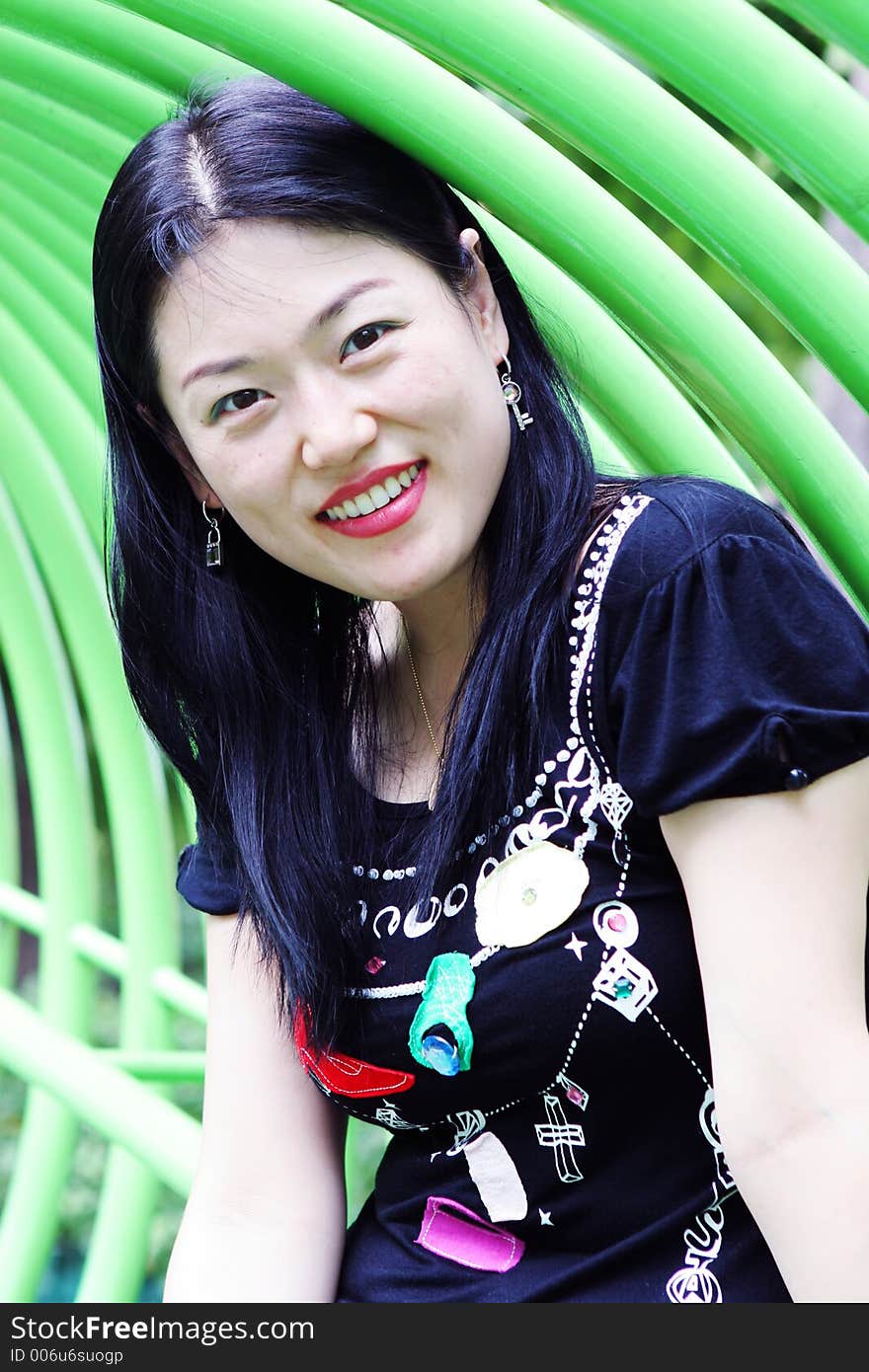 Asian woman playing in a green tunnel at the park. Asian woman playing in a green tunnel at the park