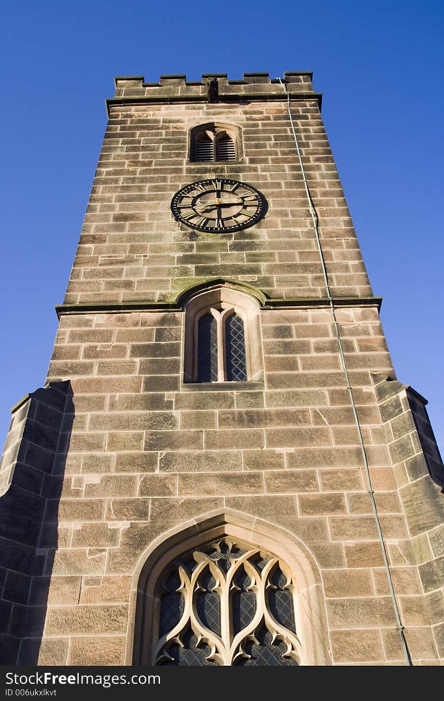 English Church Tower and clock. Arched windows and stone. Vivid blue Summer sky.