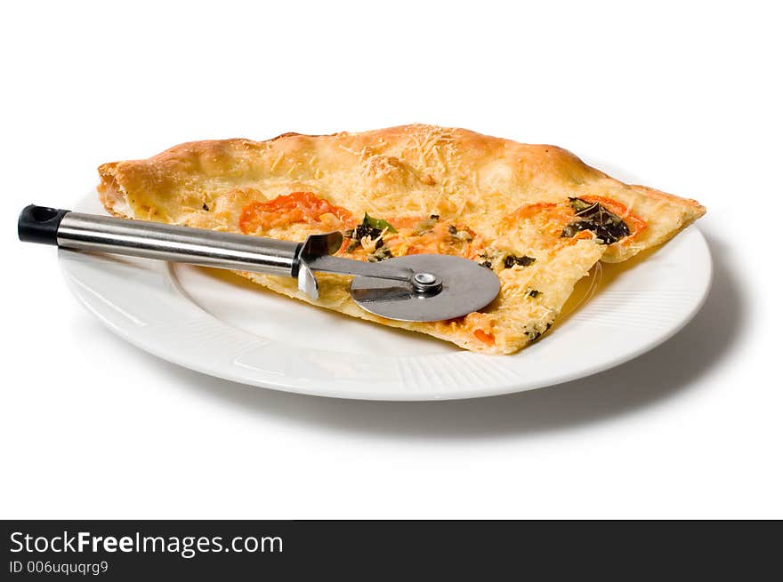 Slice of pizza on white plate with pizza cutter isolated on white.