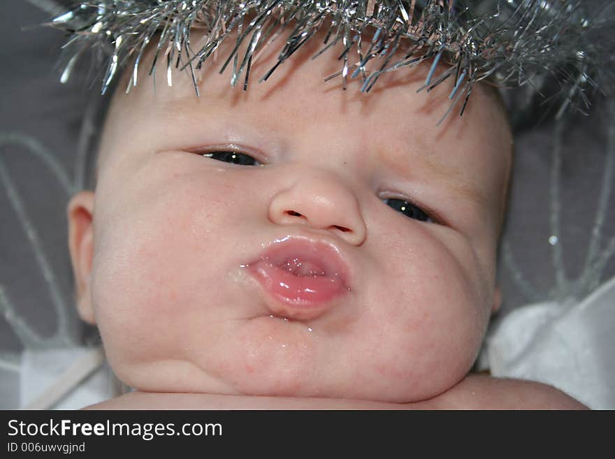 A close up of a chubby baby with a halo sticking it's tongue out. A close up of a chubby baby with a halo sticking it's tongue out.