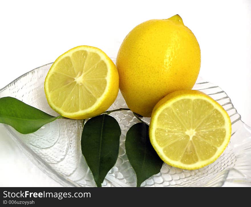 Half and whole lemon on crystal plate. Half and whole lemon on crystal plate