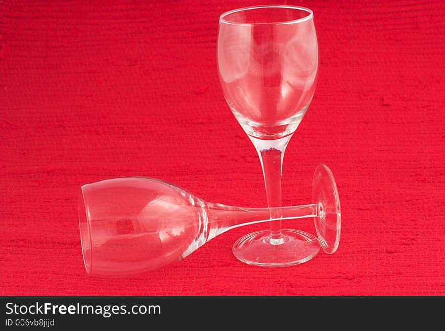 Two white wine glasses on red background