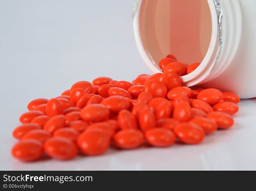 Orange pills poured out of bin isolated over white