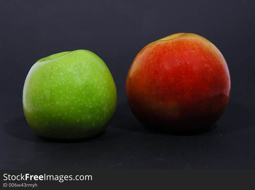 Green and red apple on black background with spotlight