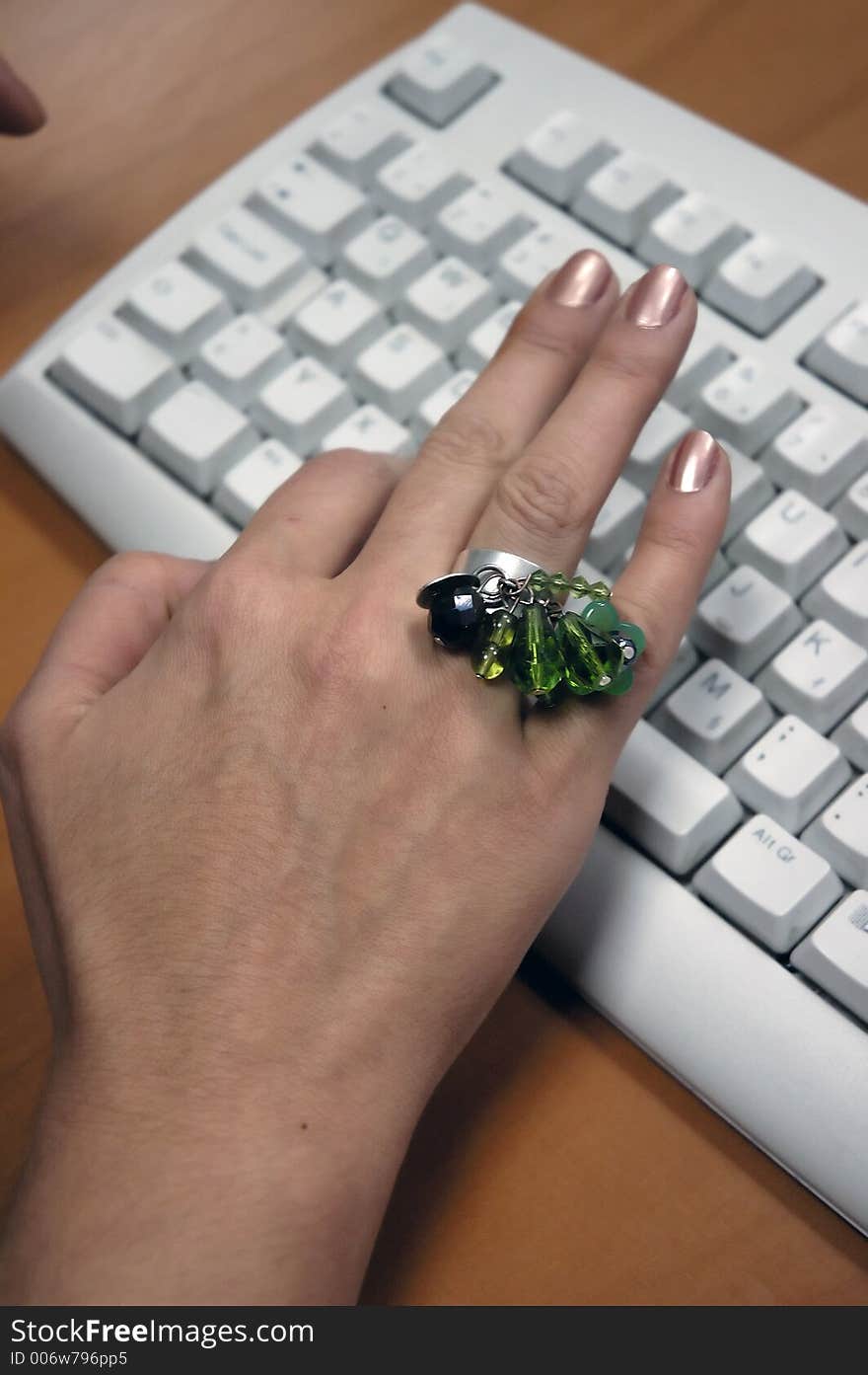 Hand with big ring is typing at the computer keyboard