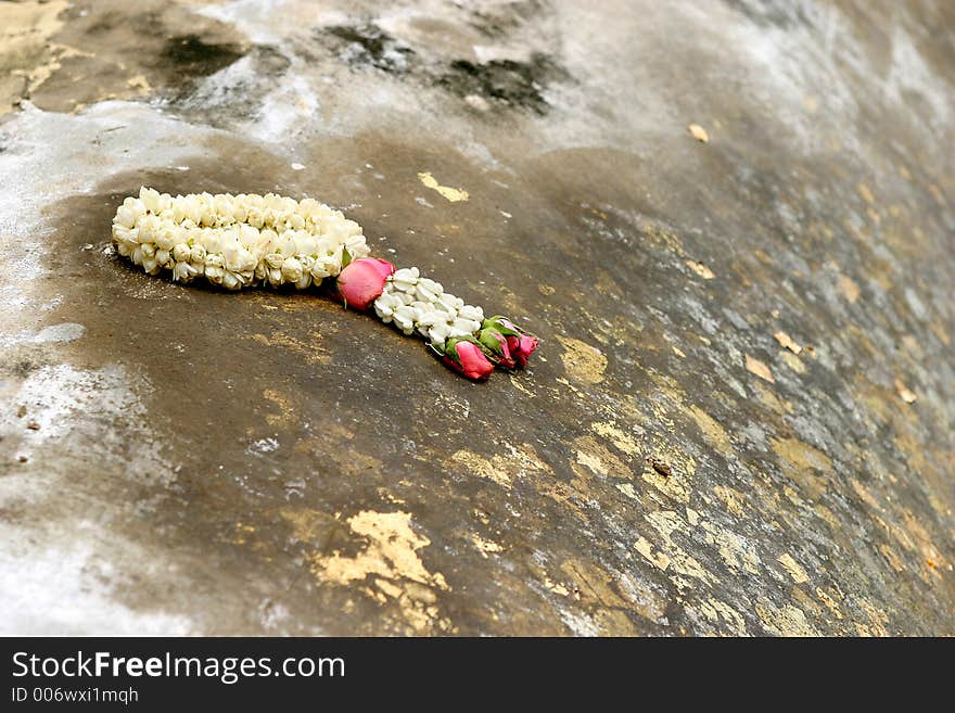 Gold pasted on Buddha body with a ring of flower. Offerred to Buddha in return of blessing