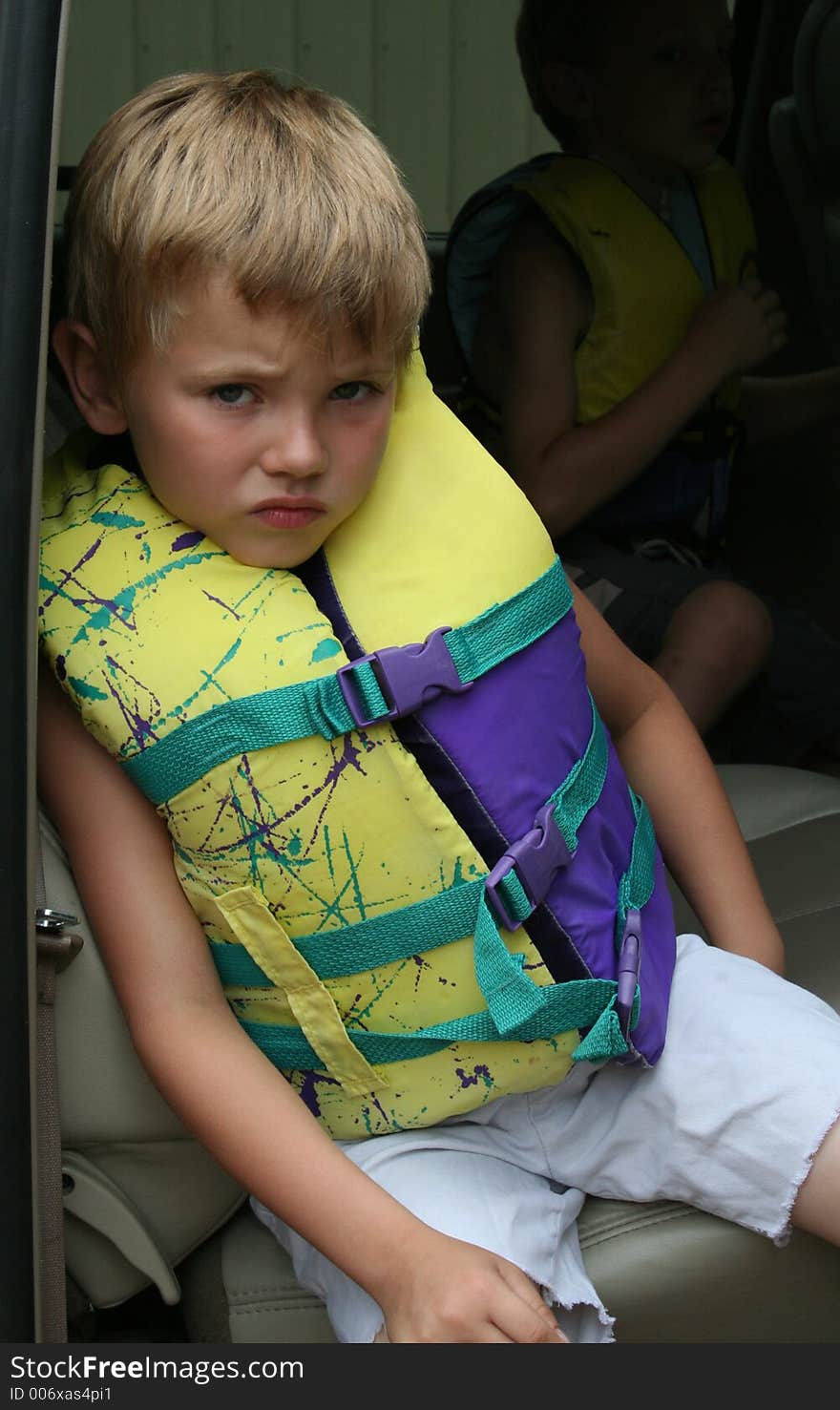 Young boy in a life jacket waiting impatiently in the vehicle to go swimming. Copyspace upper right. Young boy in a life jacket waiting impatiently in the vehicle to go swimming. Copyspace upper right.