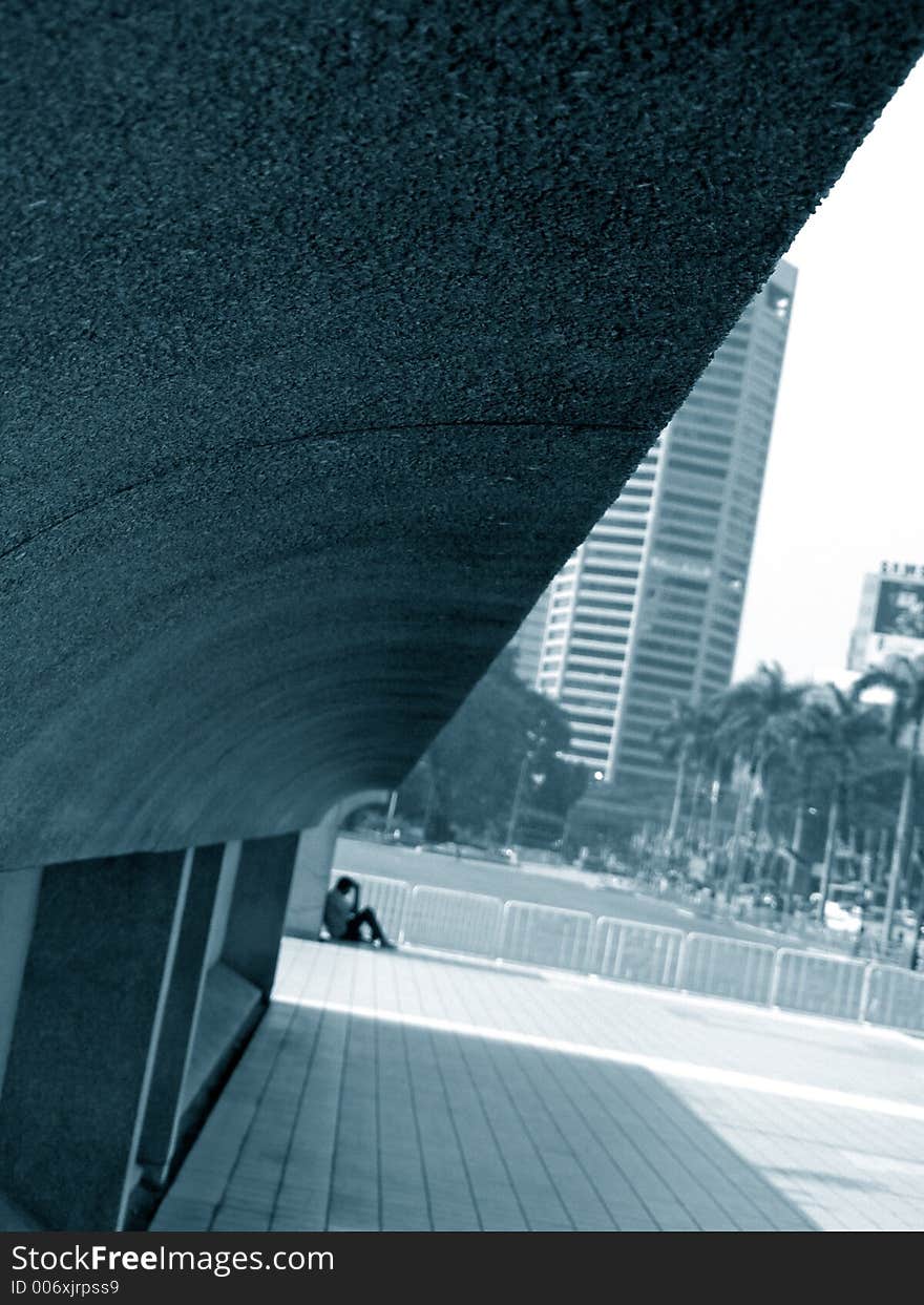 A man sitting alone, in a city background. A man sitting alone, in a city background.