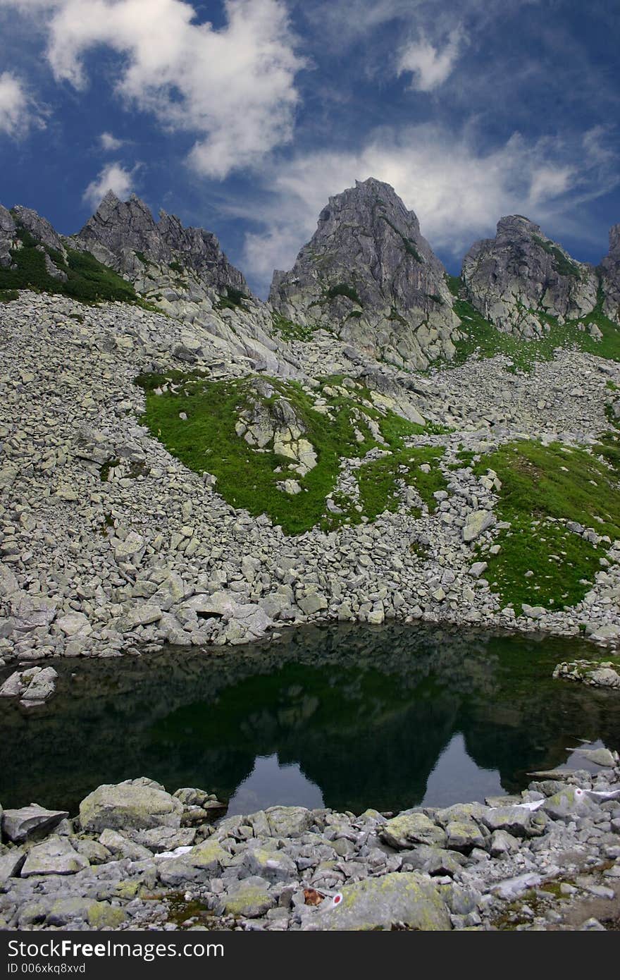 Three razor sharp mountains peak reflecting in the small glacial lake from Retezat Mountains - Romania. Three razor sharp mountains peak reflecting in the small glacial lake from Retezat Mountains - Romania