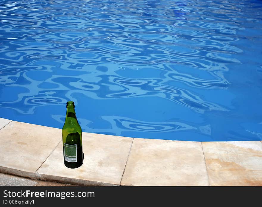 Green empty bottle of beer on the pool border