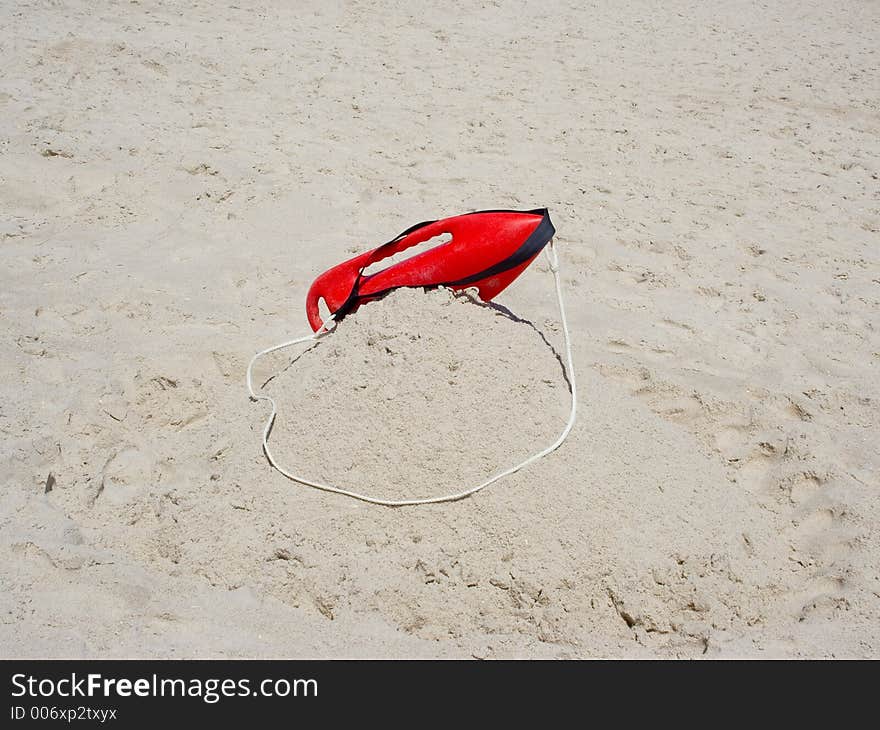 A lifeguard's float sits atop the sand ready in case of an emergency. A lifeguard's float sits atop the sand ready in case of an emergency.