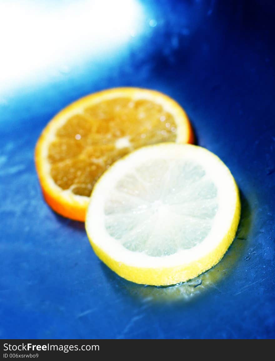 Lemon and orange slices in blue water. Lemon and orange slices in blue water