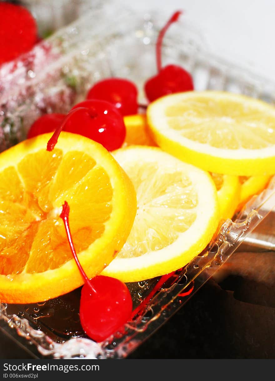 Cherries, lemons, oranges, and strawberries in a plastic container. Cherries, lemons, oranges, and strawberries in a plastic container