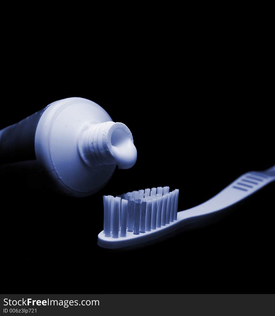 Toothbrush and toothpaste isolated on black. Tinted blue to suggest night time. Toothbrush and toothpaste isolated on black. Tinted blue to suggest night time.