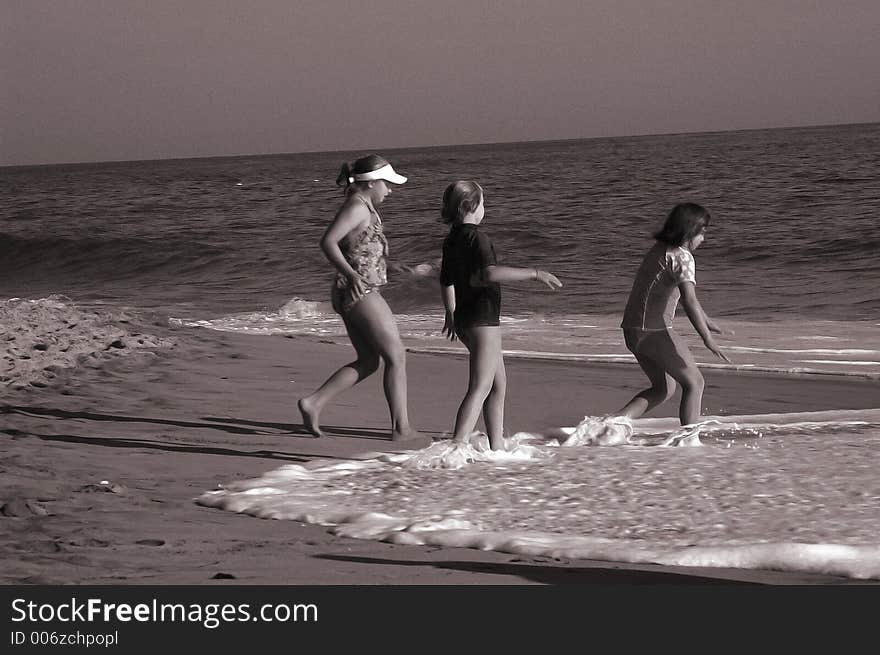 Three girls are running to the water on the beach. Three girls are running to the water on the beach