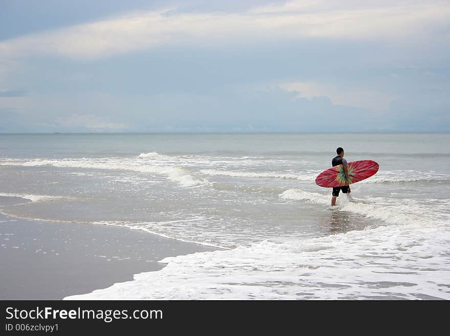 Man going into the ocean to surf. Man going into the ocean to surf