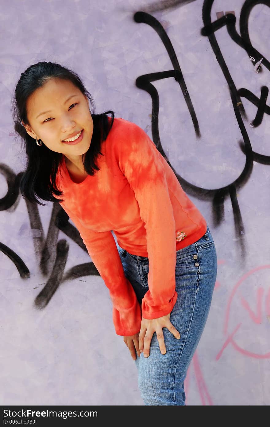 Korean woman wearing an orange top and jeans - graffiti wall. Korean woman wearing an orange top and jeans - graffiti wall