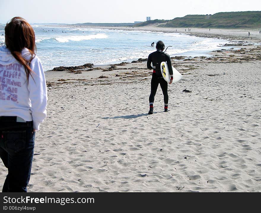 A girl and a surfer walking on the ocean beach. A girl and a surfer walking on the ocean beach.