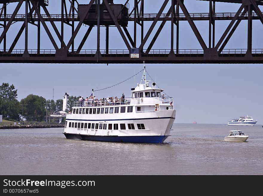 Boaters and a cruise ship tour the Cleveland Cuyahoga river - bridge is a train trestle that was raised for traffic. Boaters and a cruise ship tour the Cleveland Cuyahoga river - bridge is a train trestle that was raised for traffic.