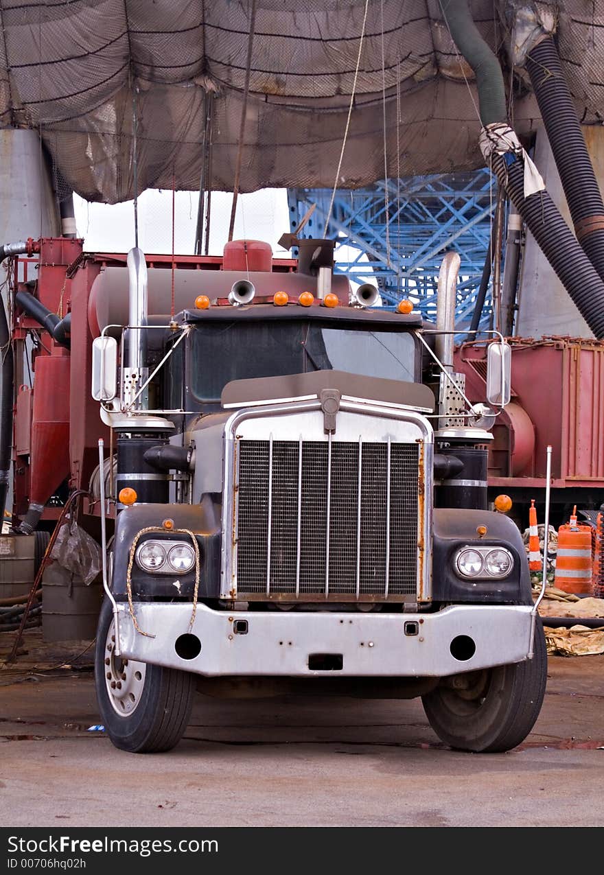 A large  tractor trailer truck working on job site. Painting a very large city bridge overhead and draped. A large  tractor trailer truck working on job site. Painting a very large city bridge overhead and draped.